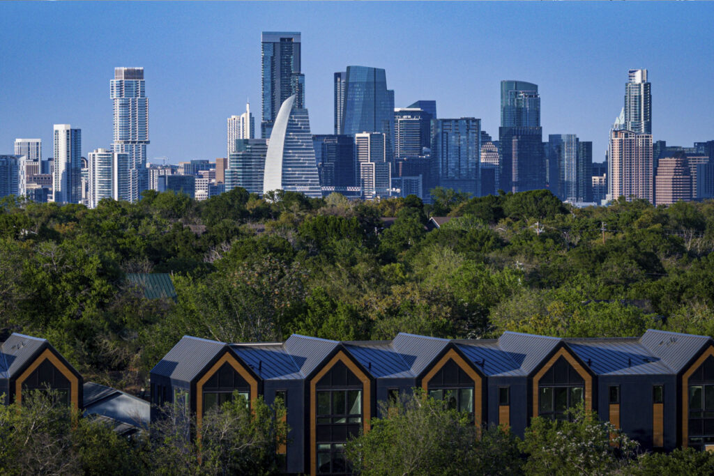 Aerial view of 4101 Menchaca modern townhomes in South Austin with the Austin, Texas downtown skyline in the background. Highlighting the project's proximity to downtown and the 78704 lifestyle.